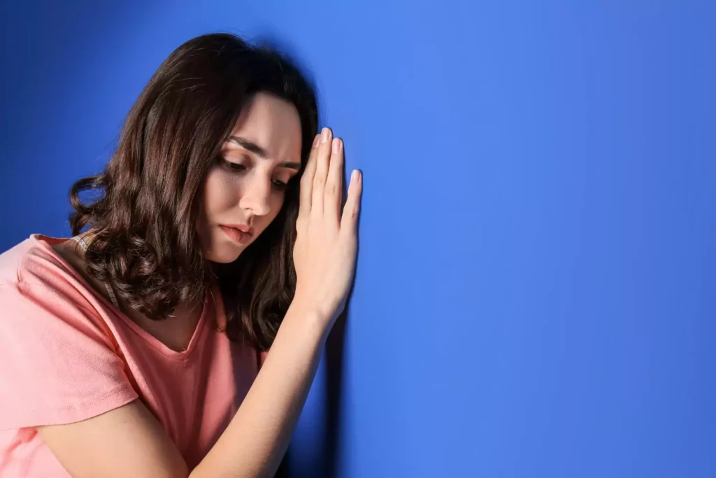 a woman suffering from depression leaning against a blue wall