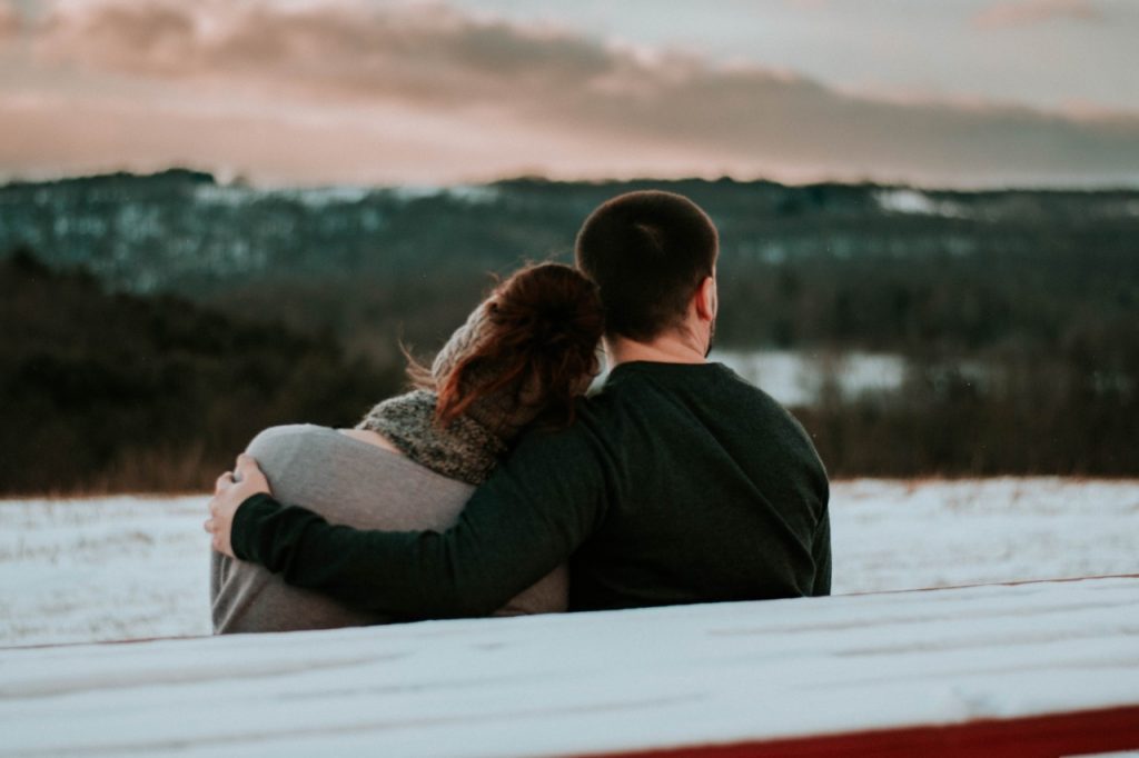 woman and man sitting on bench overlooking lake