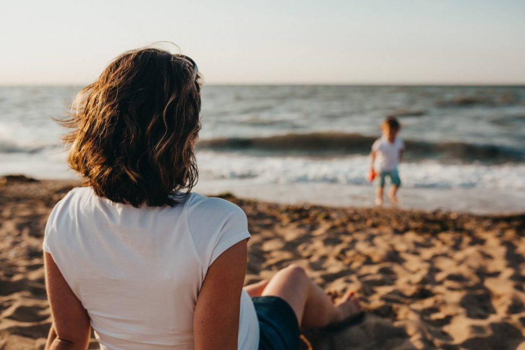 Woman on beach watching a child play