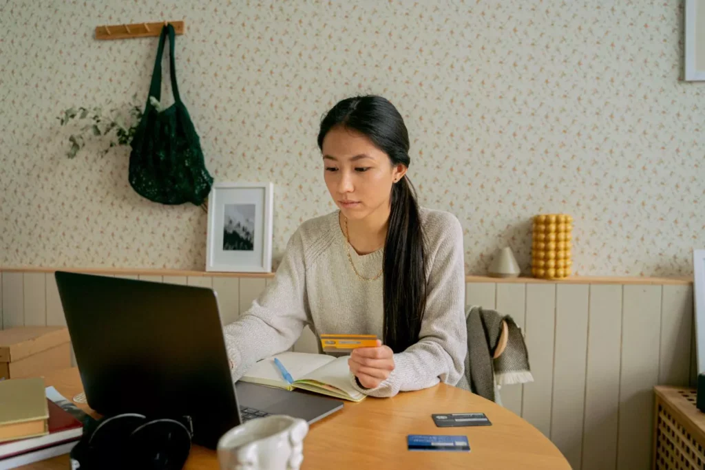 a women dealing with debt looking at her computer with her credit card in hand