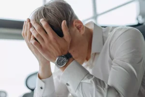 a man, feeling shame, with his head in his hands
