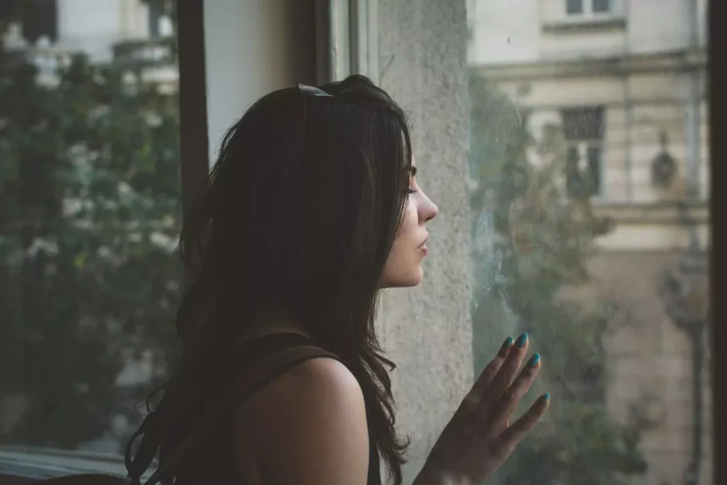a woman looking out a window, feeling unlovable