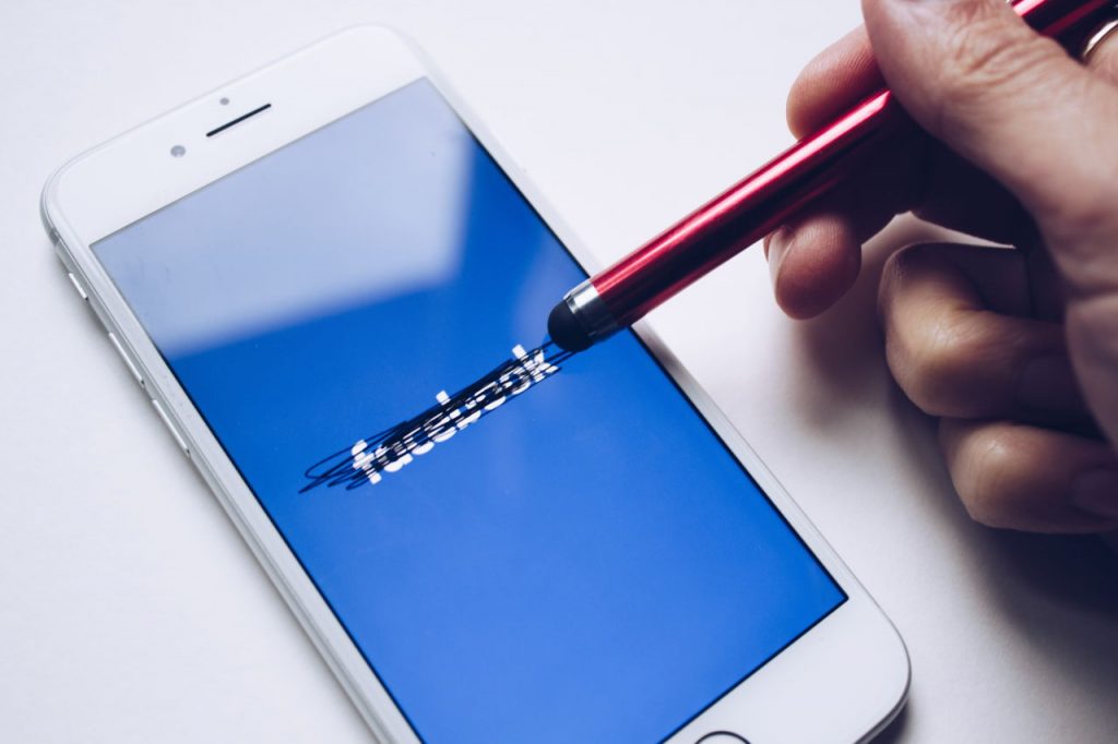 a person scribbling out Facebook on his mobile with a stylist