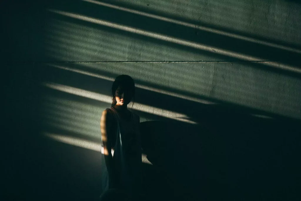 a woman standing in the shadows, feeling invisible