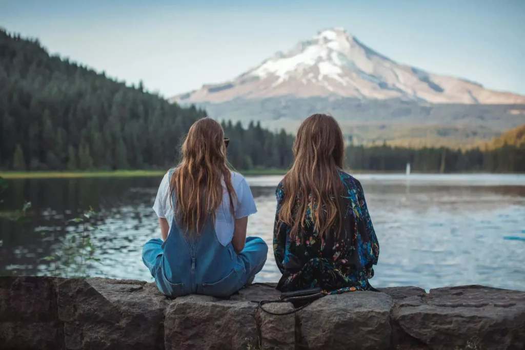 two women sitting by a lake showing care for one another
