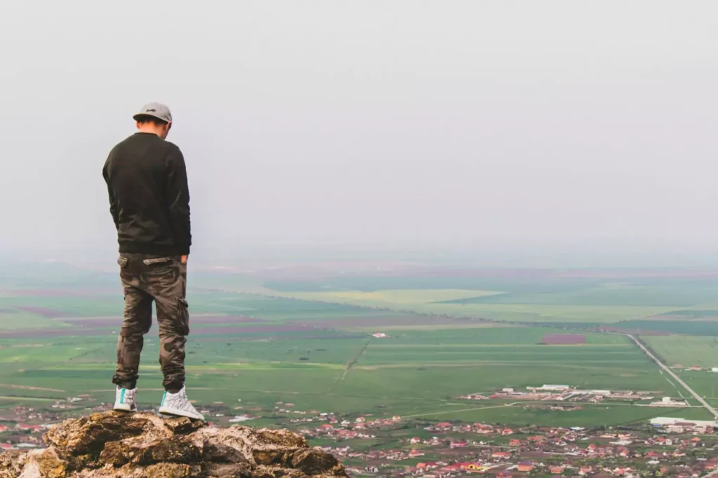 man with hands in pockets, overlooking the city and thinking about his friends that leave the faith
