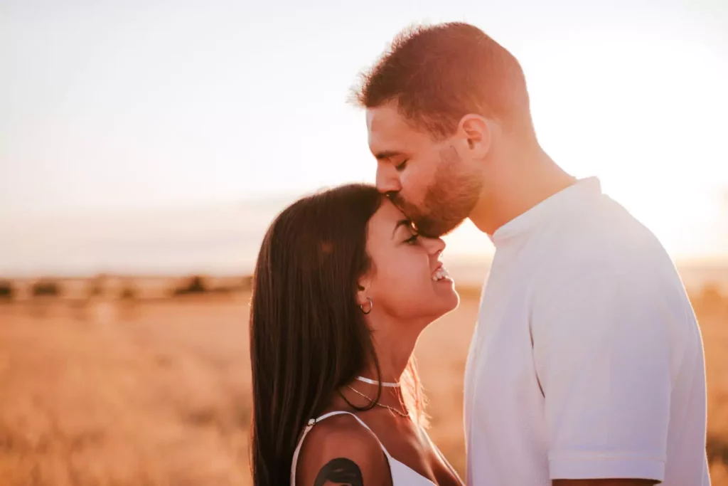 a guy kissing his girlfriend's forehead