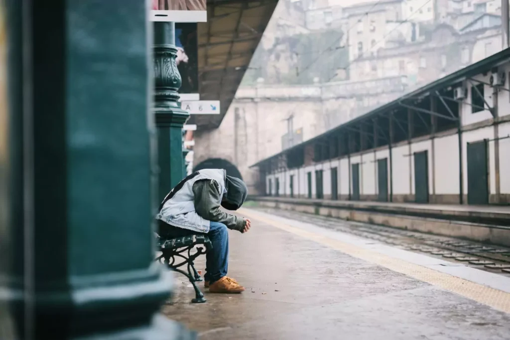 a man sitting on a bench with his head down, caring about others' opinions
