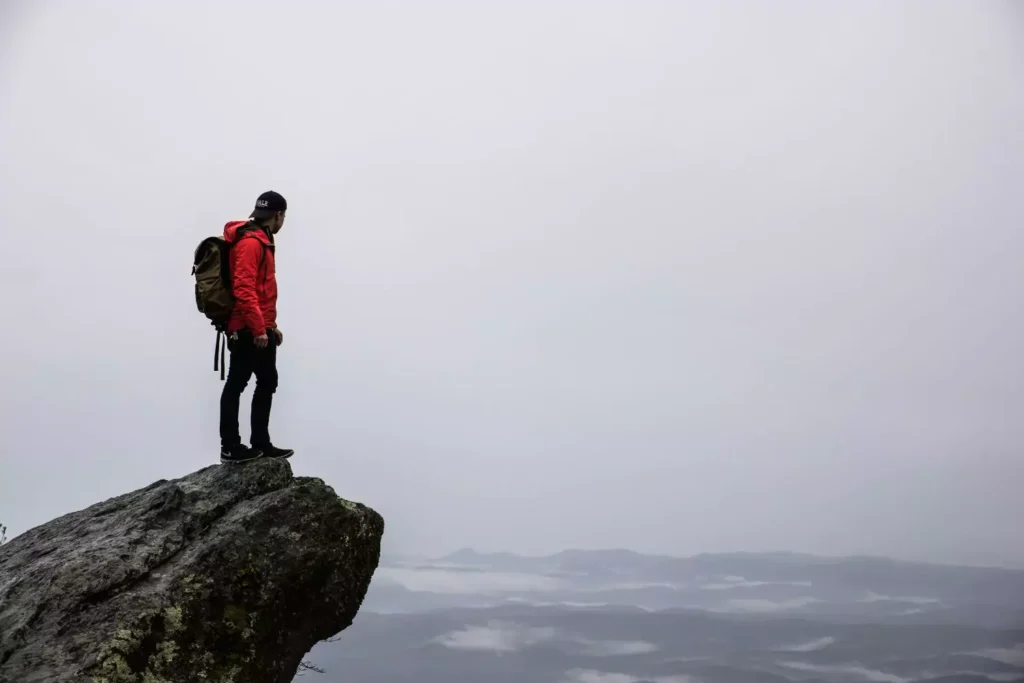 a guy standing on a cliff, seeking a comfortable situation
