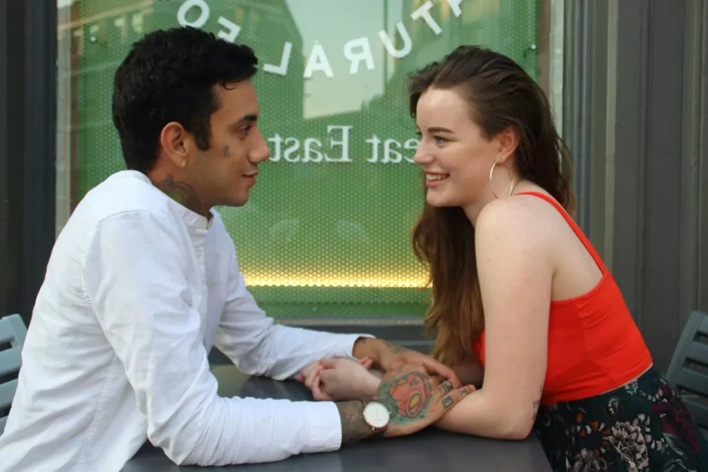 a couple at an outdoor table, looking at each other an smiling. Is marriage hard?