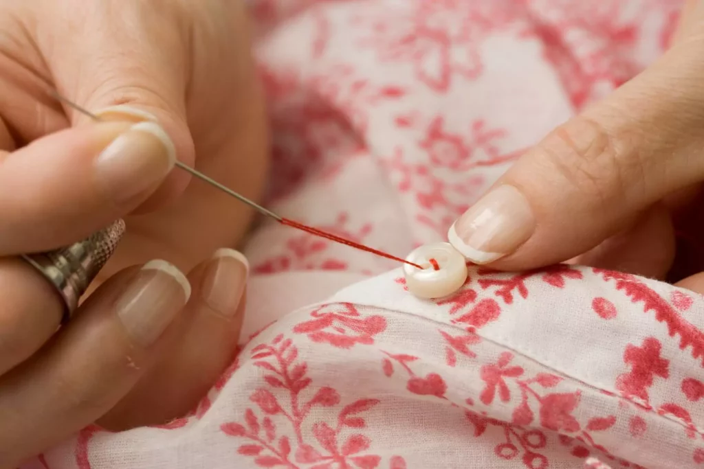 a woman sewing on a button, thinking about her calling