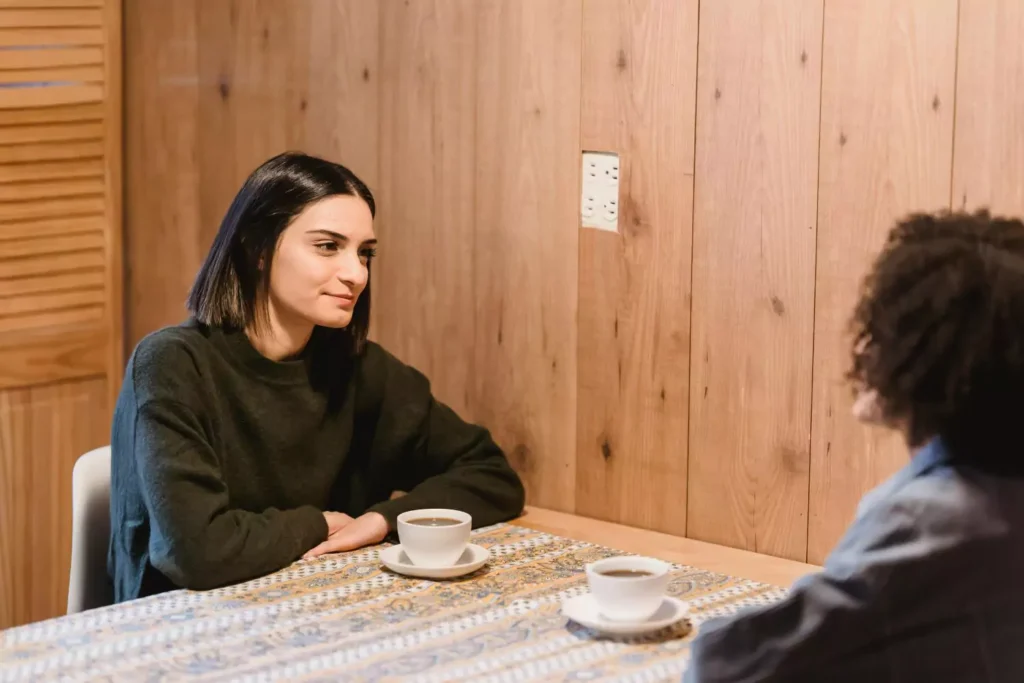 two women having a conversation over coffee, one is a people-pleaser.