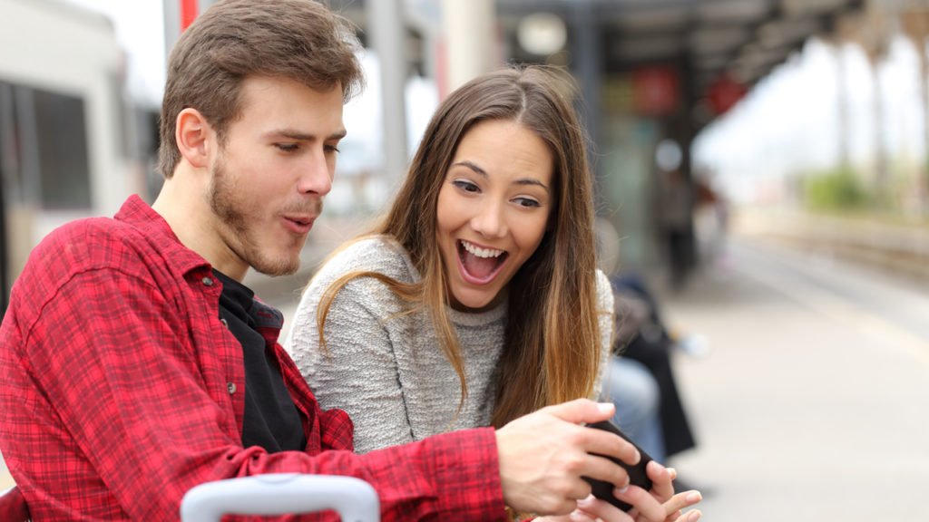 couple sitting together joyfully looking at phone